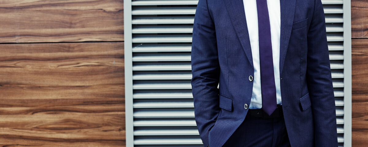 Well-dressed young businessman standing at the wall